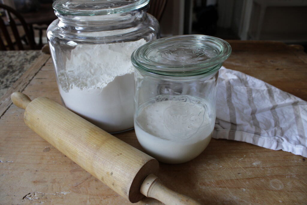 Jar of flour and jar of fresh homemade sourdough sitting on counter.